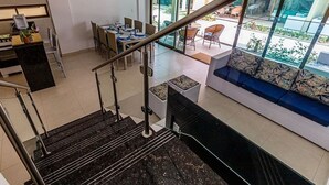 A modern interior with a staircase, a dining area, and a seating area with a view. - Beira Mar C Piscina e Area Gourmet 113D (Ipojuca)