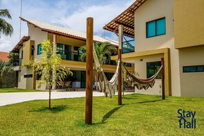 A modern hotel with a two-story structure, a covered outdoor seating area, and a hammock in the courtyard. - Beira Mar C Piscina e Area Gourmet 113D (Ipojuca)