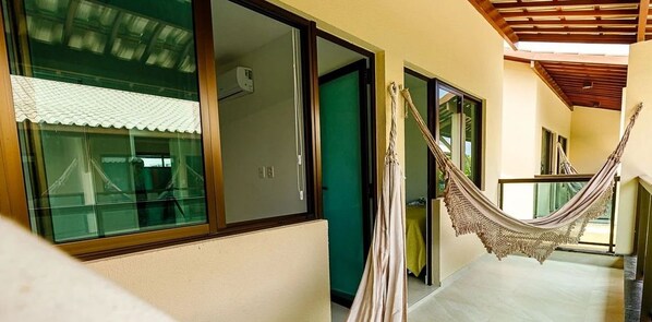 A corridor with a hammock, a door, and a window with a curtain. - Beira Mar C Piscina e Area Gourmet 113D (Ipojuca)