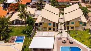A resort with multiple buildings, a swimming pool, and outdoor seating areas. - Beira Mar C Piscina e Area Gourmet 113D (Ipojuca)