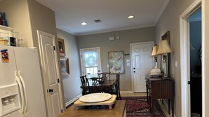 A kitchen with a wooden countertop, white refrigerator, dining table with chairs, and a rug.