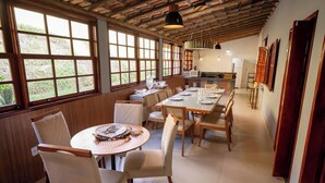 Un comedor amplio con ventanas grandes, vigas de madera en el techo y una mesa larga dispuesta para comer.