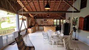 Una cocina amplia con una isla de ladrillo, sillas blancas y una hamaca colgante.