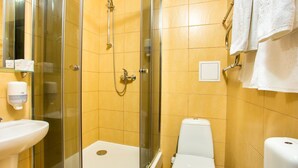 Un baño con cabina de ducha de vidrio, un lavabo blanco y un inodoro.