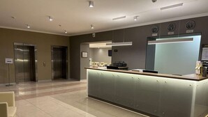 Un moderno vestíbulo de hotel con mostrador de recepción, zona de estar y ascensores.