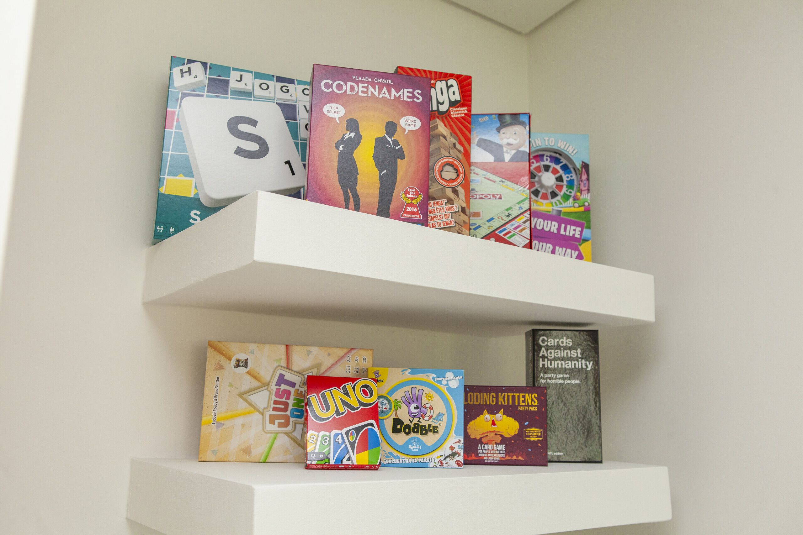 A shelf with various board games including Codenames and Uno.