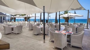 An outdoor dining area with tables and chairs, large umbrellas, and a view of the ocean. - Sol Lanzarote All Inclusive (Puerto del Carmen)