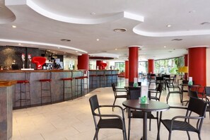 A modern bar area with stools and a counter, surrounded by tables and chairs in a spacious indoor setting. - Sol Lanzarote All Inclusive (Puerto del Carmen)