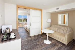 Une chambre d’hôtel avec un canapé, une petite table, une machine à café et un balcon avec vue.