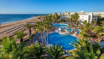 Un complex turístic amb diverses piscines, accés a la platja i palmeres.