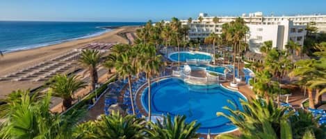 A resort with multiple swimming pools, beach access, and palm trees.
