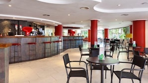A modern restaurant with a curved bar, red pillars, and black chairs. - Sol Lanzarote All Inclusive (Puerto del Carmen)