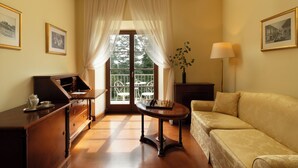A room with a wooden desk, a sofa, a lamp, and a window with curtains. - Dvorec Jeruzalem (Ljutomer)