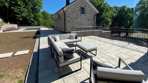 A stone building with a chimney, a stone patio with outdoor furniture, and a metal railing. - Rustic stone house-Casa Tilia-with pool and sauna, in peaceful village near sea. (Crno)