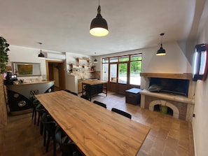 A kitchen with a wooden table, chairs, pendant lights, a built-in oven, and a view of the outdoors.