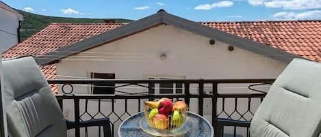 Enjoy a serene view from this balcony with a round table and two comfortable chairs.