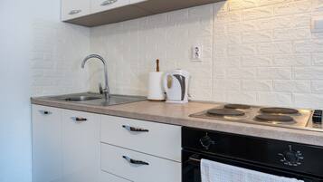 Een koelkast, een oven, een kookplaat, kookgerei, borden en bestek