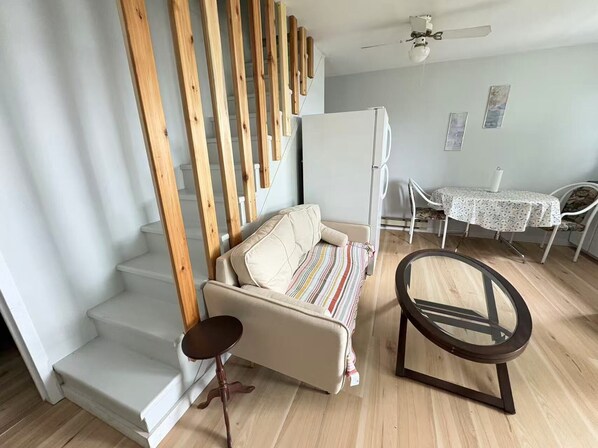 A living room with a sofa, a small table, a chair, and a staircase with wooden railings.