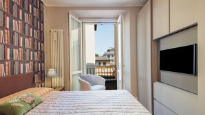 Een slaapkamer met een bed, een boekenkast, een televisie en een balkon.