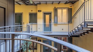 Een meerlaags woongebouw met balkons, trappen en deuren.