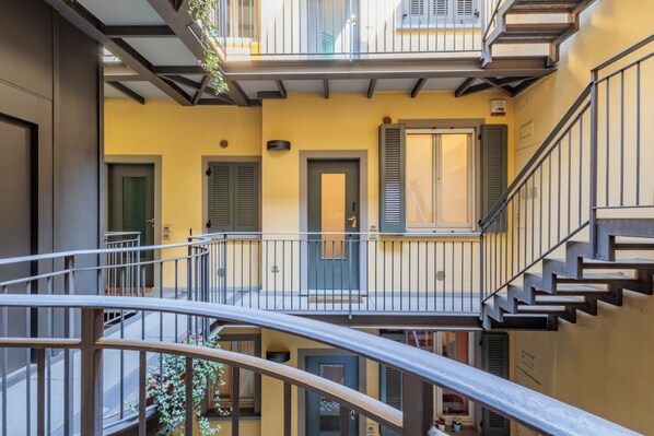 A multi-level residential building with balconies, staircases, and doors.