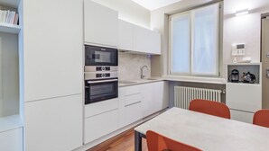 Een moderne keuken met witte kasten, een ingebouwde oven en een raam boven de gootsteen.