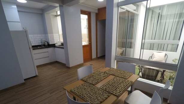 A modern kitchen with white cabinets, a wooden countertop, and a built-in oven. - Apartment 5 minutes from downtown (Paracas)