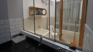 A bathroom with a large window, a bathtub, a sink, and a mirror. - Apartment 5 minutes from downtown (Paracas)