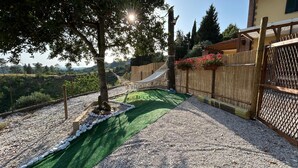 Un jardin avec un hamac, une clôture en bois et une vue sur la campagne.