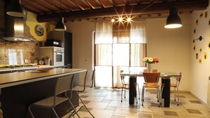 Une cuisine avec un îlot central, une table à manger avec des chaises et une fenêtre avec des rideaux.