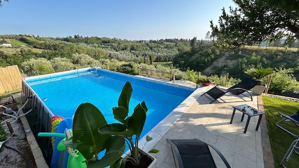 Une piscine rectangulaire à l’eau d’un bleu limpide, entourée d’une terrasse carrelée. On y trouve des chaises longues et une petite table.