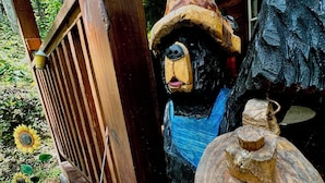 Une sculpture en bois représentant un ours portant un chapeau et tenant une pancarte sur laquelle on peut lire : « Got Shine ».