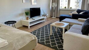 A modern living room with a flat-screen TV, a sofa, a small table, and a floor lamp.