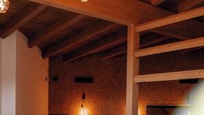 Ein modernes Wohnzimmer mit einer Eckcouch, Holzbalken und einer Steinwand.