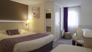 Una habitación de hotel con una cama grande, un escritorio con silla, una mesita, un espejo y una ventana con cortinas.