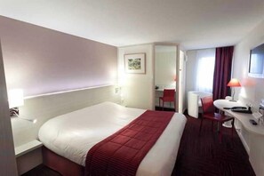 A hotel room with a large bed, a desk, a chair, a small table, and a TV. - The Originals City, Hotel Alizea, Le Mans Nord (Saint-Saturnin)