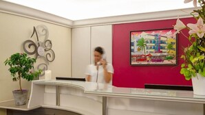 Ein Hotel-Empfangsbereich mit modernem Design, ausgestattet mit einem Glastresen, einer Uhr und einem Stadtbild.