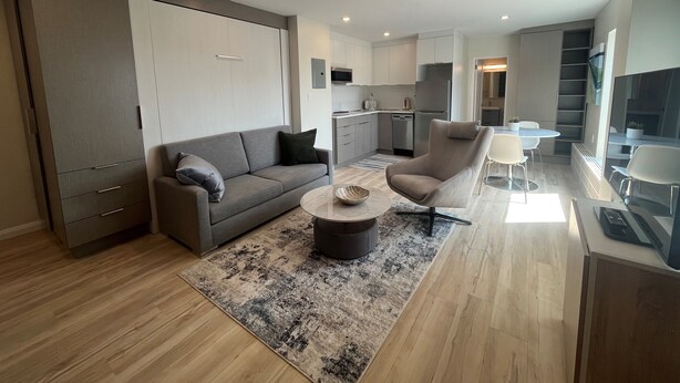 A modern apartment with a living room, kitchen, dining area, and a balcony.