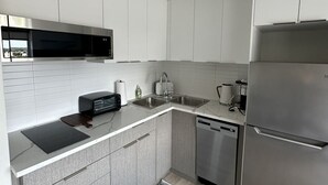 A modern kitchen with white cabinets, stainless steel appliances, and a striped rug.