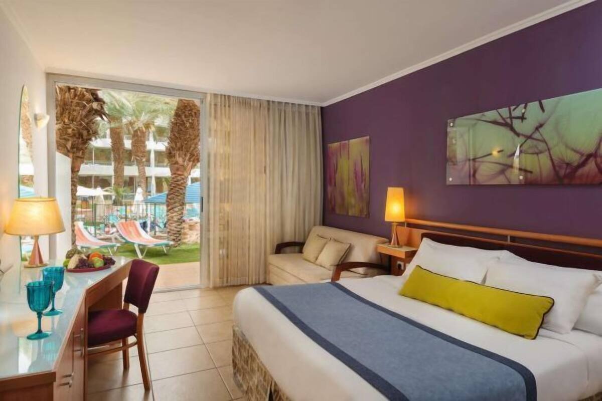 Une chambre d’hôtel avec un lit, un bureau et une vue sur l’espace extérieur de la piscine.