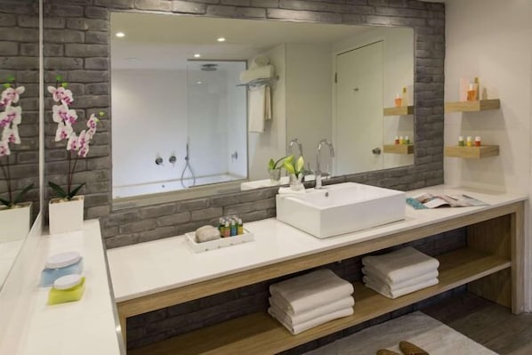 A modern bathroom with a large mirror, white sink, and wooden vanity. - Leonardo Club Eilat - All Inclusive (Eilat)