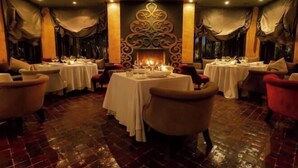 Un restaurant avec des tables rondes, des chaises et un mur décoratif.