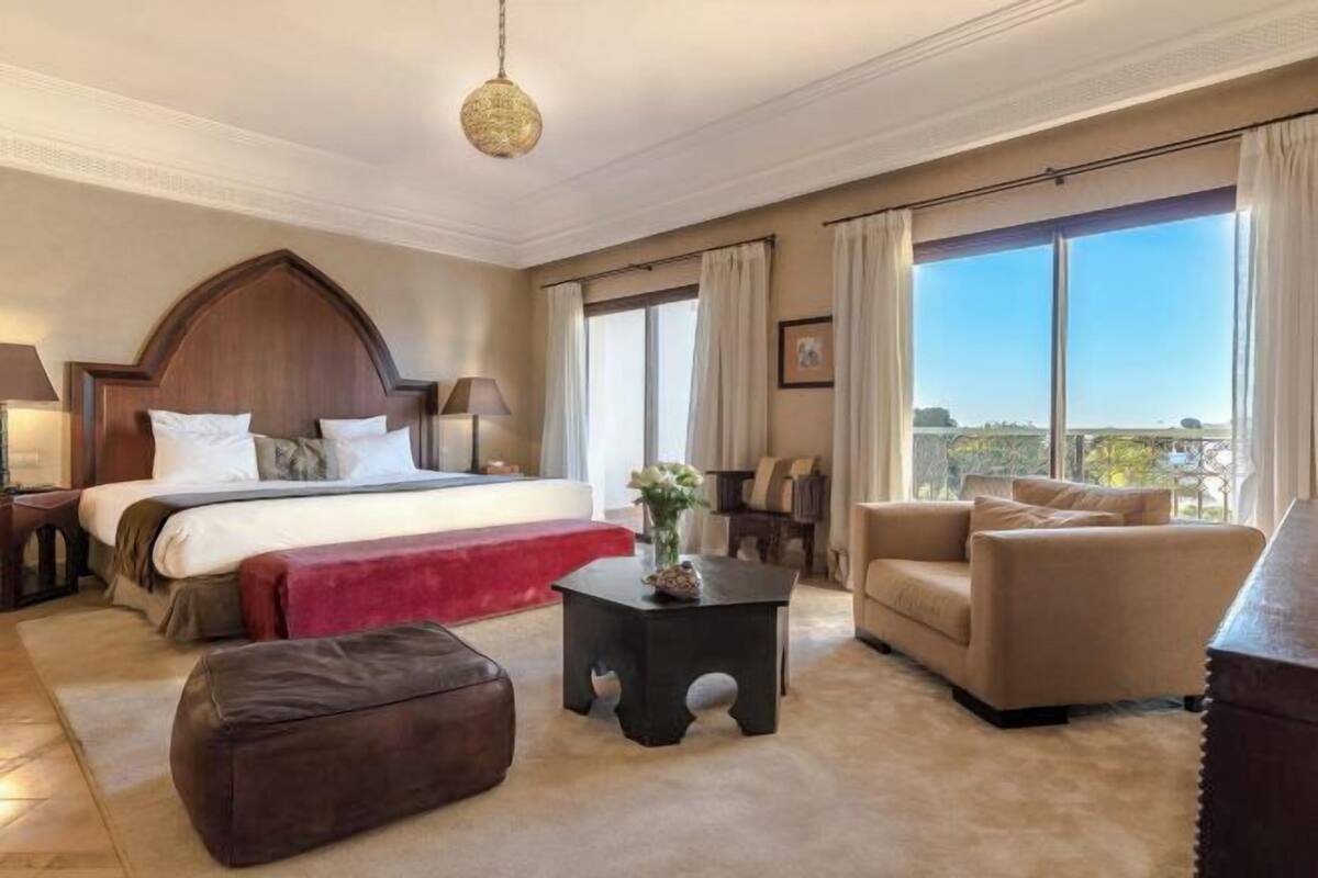 Une chambre d’hôtel avec un grand lit, un canapé, une petite table et une vue sur l’extérieur.