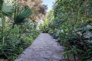 A stone pathway surrounded by lush greenery. - Le Riad Villa Blanche (Agadir)