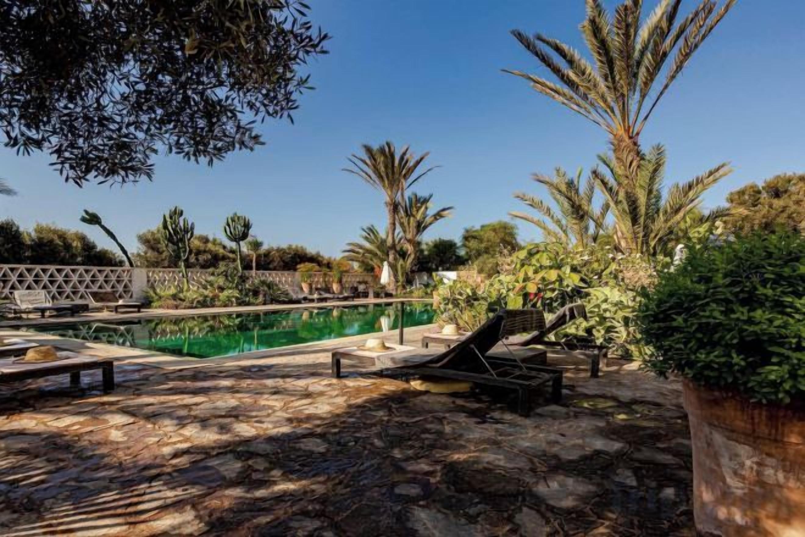 A pool area with lounge chairs and a stone patio.
