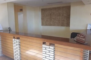 A reception desk with a sign reading 'Reception,' a wall-mounted artwork, and a chair. - Sufetula Hotel (Sbeitla)