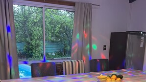 Un comedor con una mesa larga, sillas y un bol de fruta.