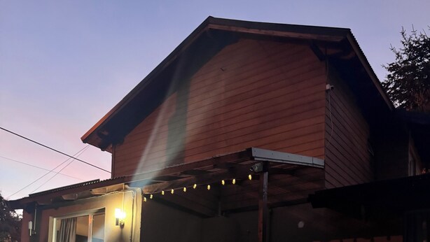 Una casa con piscina, terraza cubierta y guirnalda de luces.