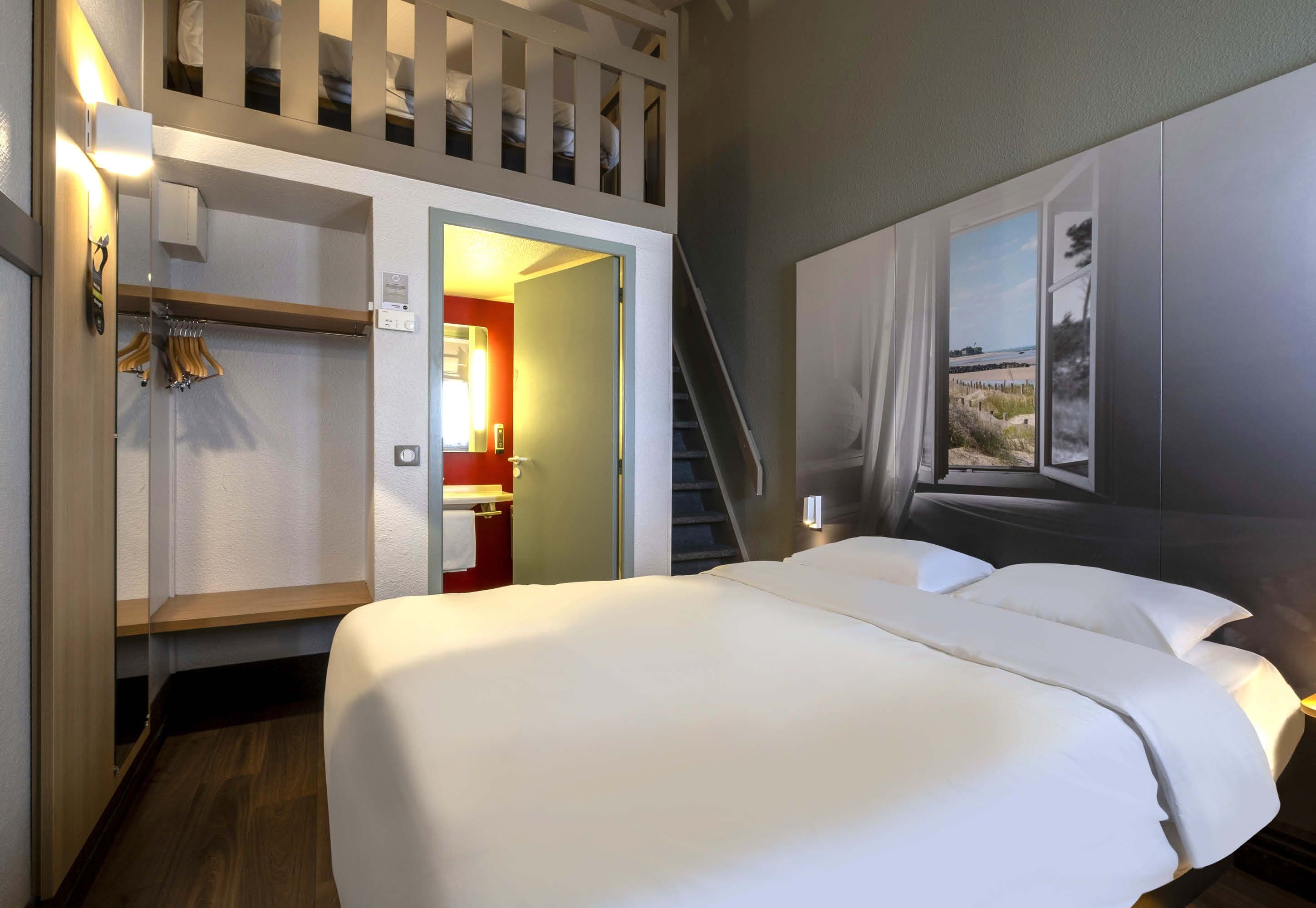 A hotel room with a bed, a wardrobe, a bathroom, and a staircase.