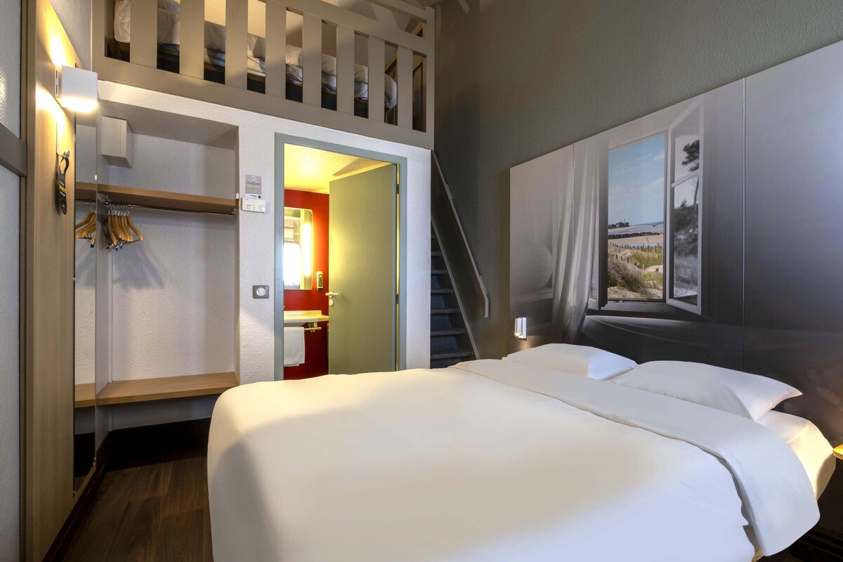 A hotel room with a bed, a wardrobe, a bathroom, and a staircase.